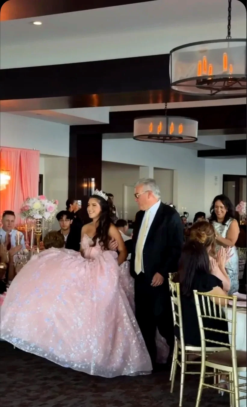 Quinceañera in a blush gown entering the ballroom