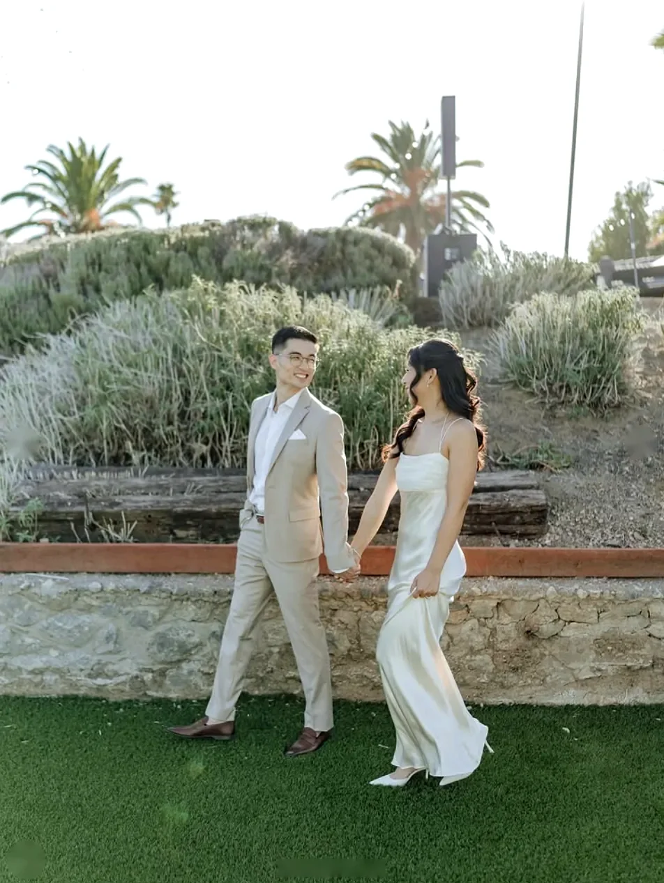 Couple walking hand in hand across a garden lawn